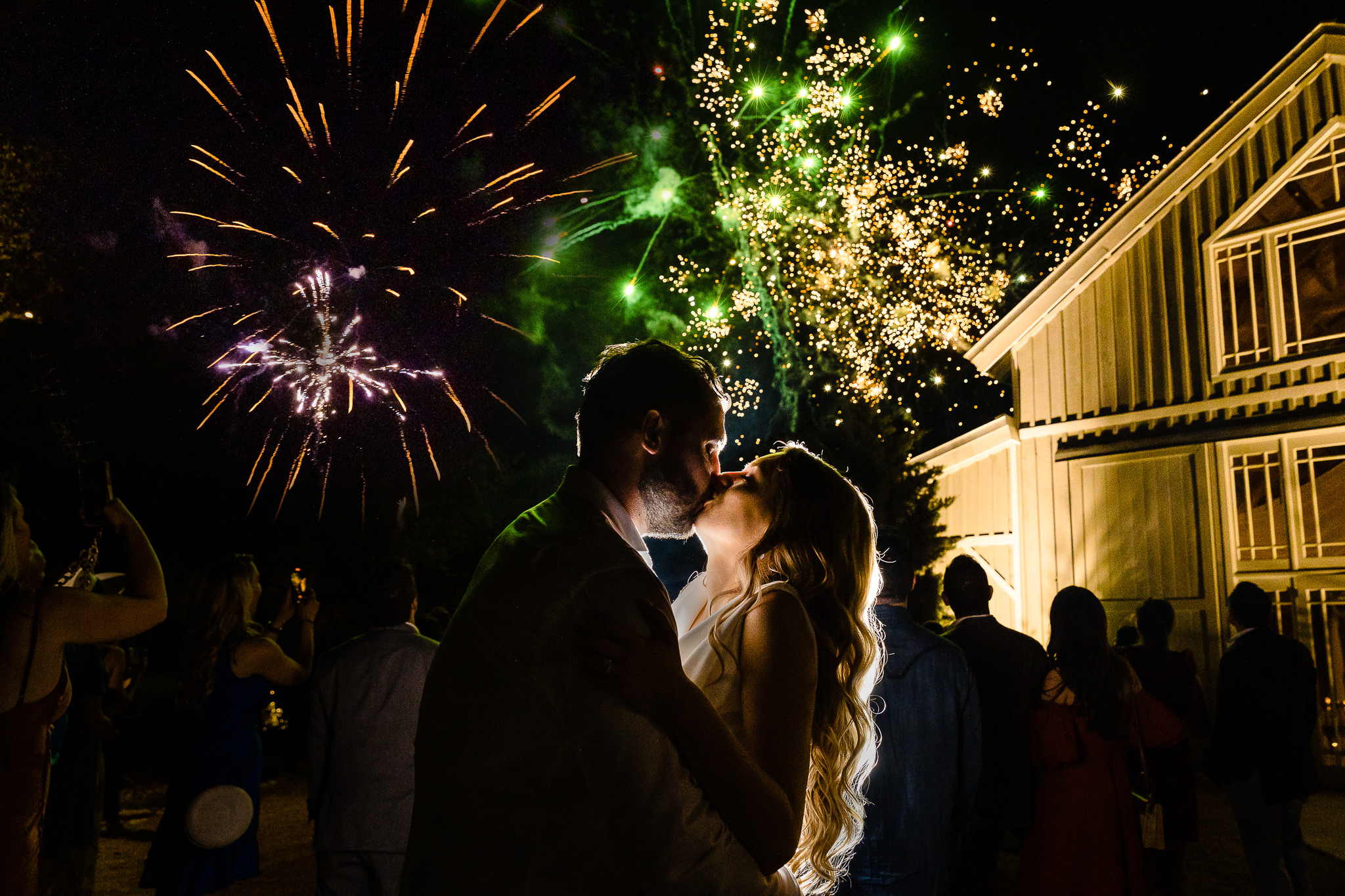 Couple kisses during fireworks at night at the close of their wedding reception