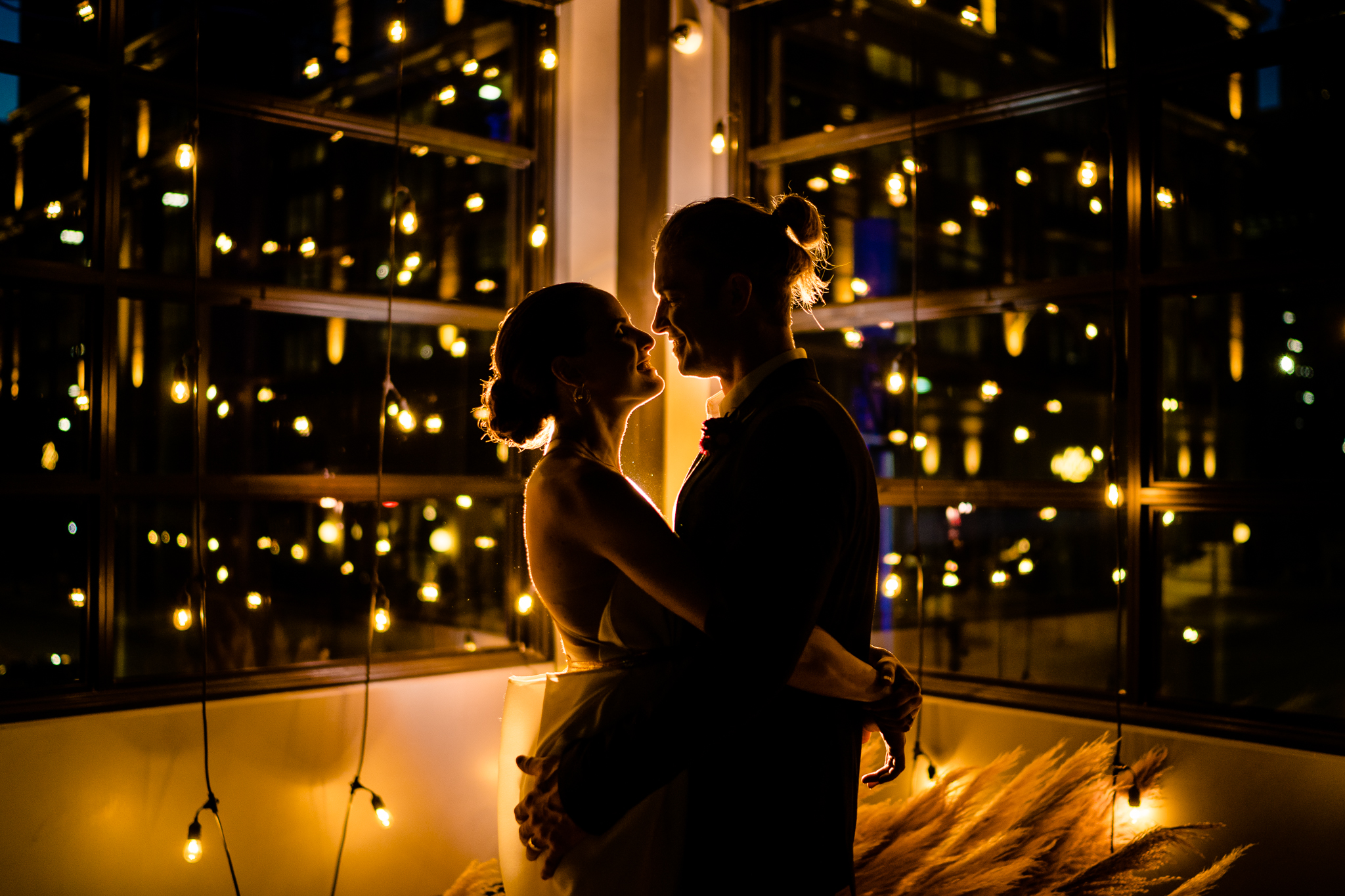 silhouette of couple surrounded by golden string lights and candles in downtown austin warehouse
